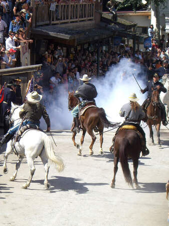 Eine Gruppe reitet auf Pferden durch eine Straße in Pullman City Westernstadt im Bayerischen Wald.